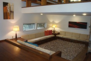 1.The sunken sitting area with built-in sofas. Art work: “That’s A Maybe” by Sys Oppenlander (left) and “So What” by Larry James (right).  Photo by Sarah Sonke, AuctionFirst®